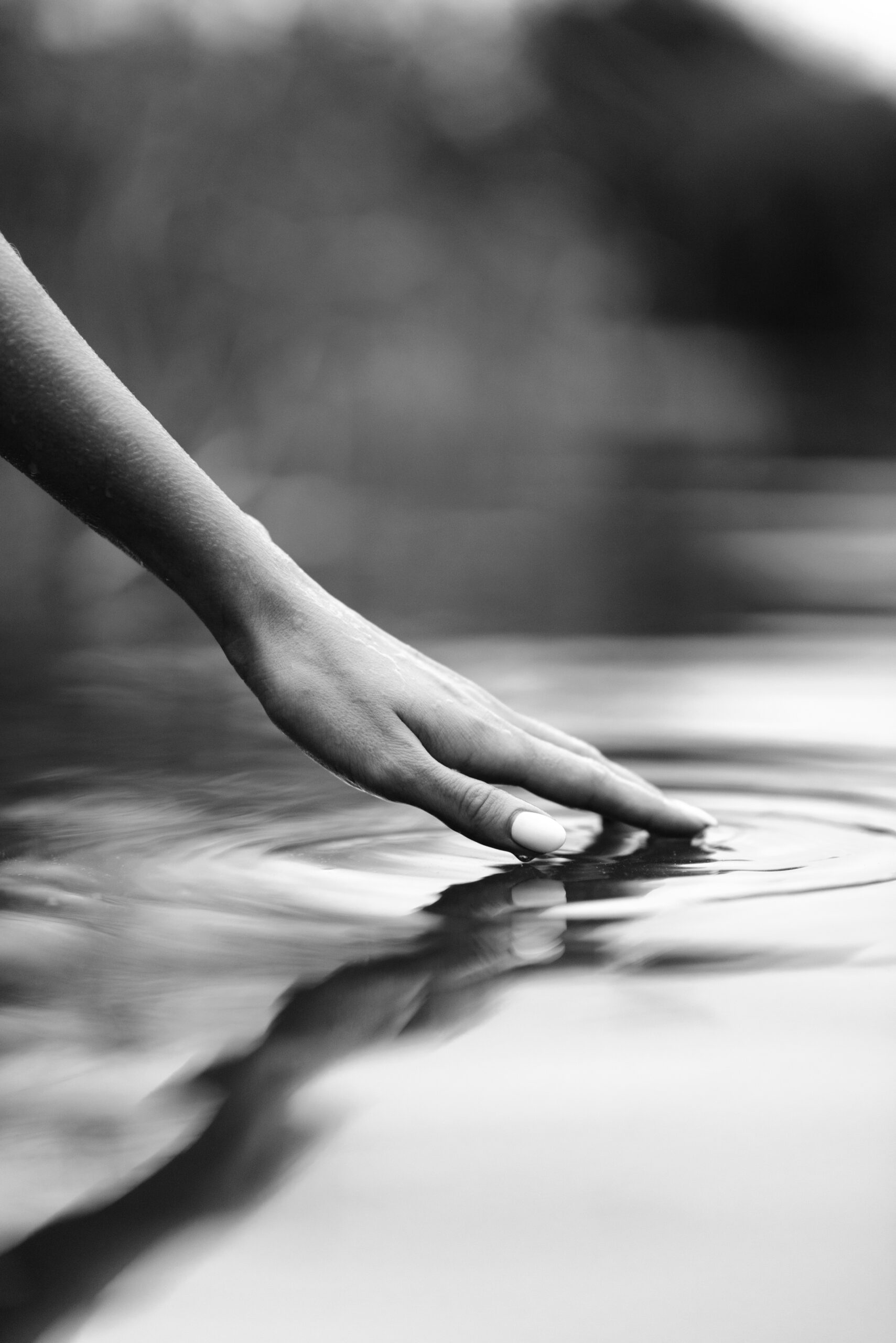 Young woman's hand touching the water in the sea
